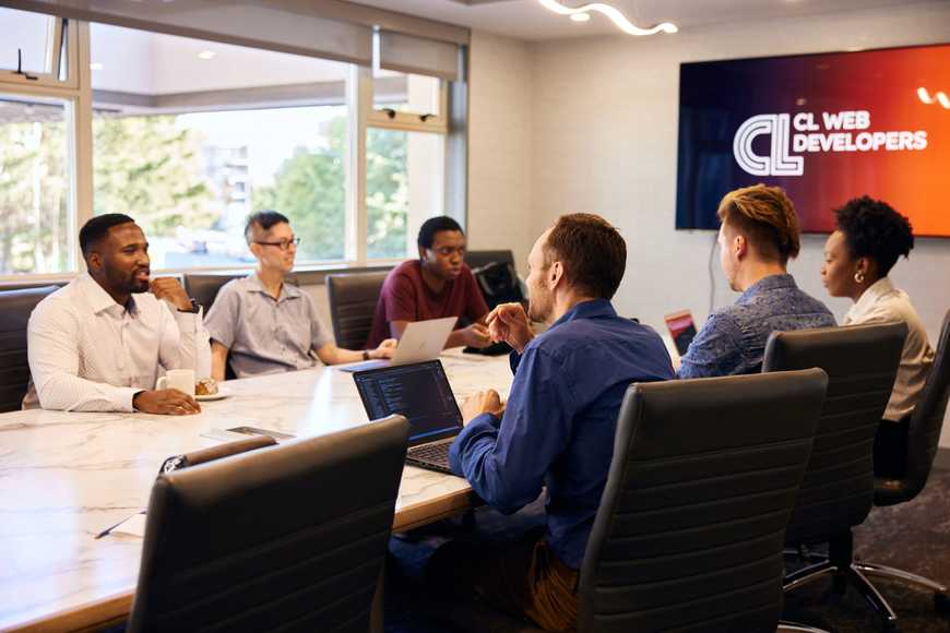 The team sitting around a boardroom table working and discussing.